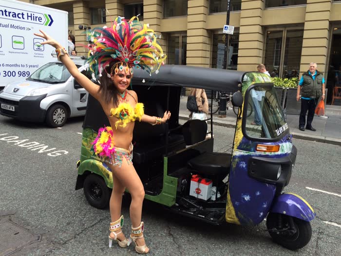 Carnival dancer beside a hand-painted tuk tuk in central London