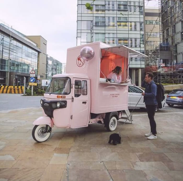 Pale pink tuk tuk vending unit serving on a city street