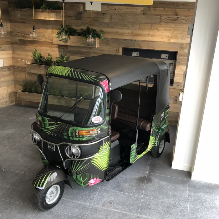 Tropical-wrapped tuk tuk on display inside a venue