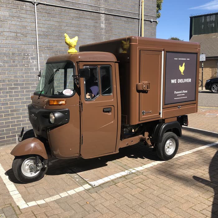 Brown box-body tuk tuk delivery van with gold branding