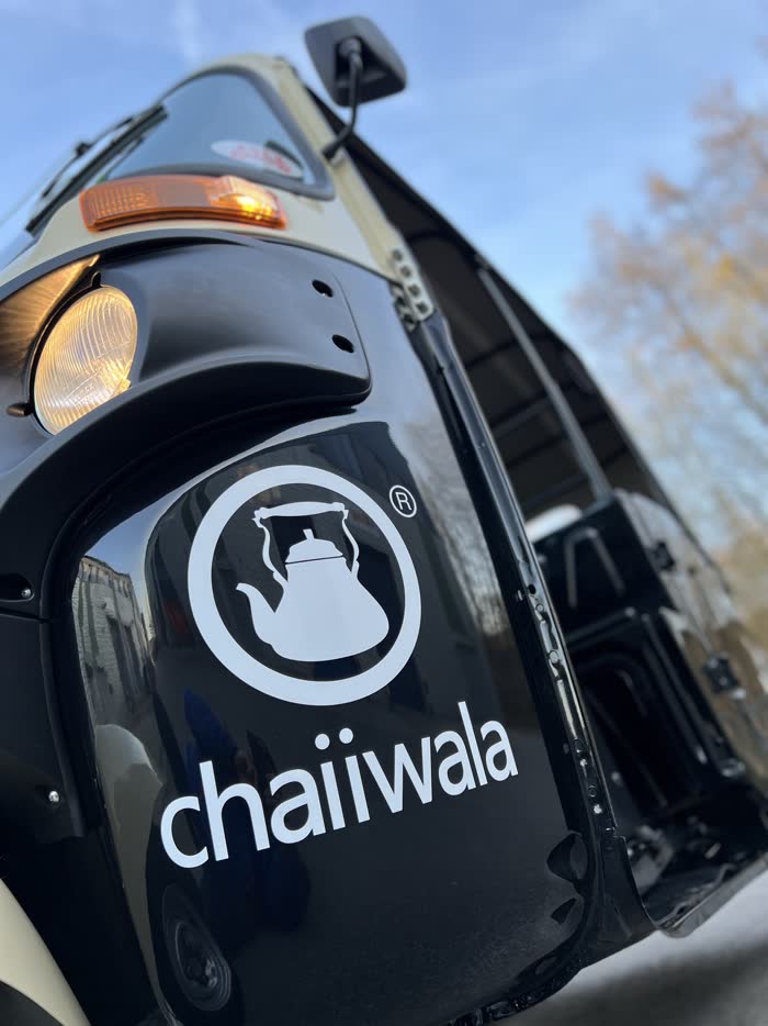 Close-up of the Chaiiwala teapot logo on a tuk tuk side panel